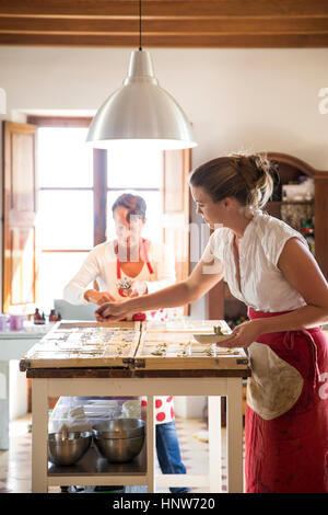Young woman applying dried lavender to soap bars in handmade soap workshop Stock Photo