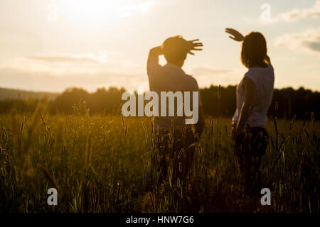 Couple looking out at sunset in field Stock Photo