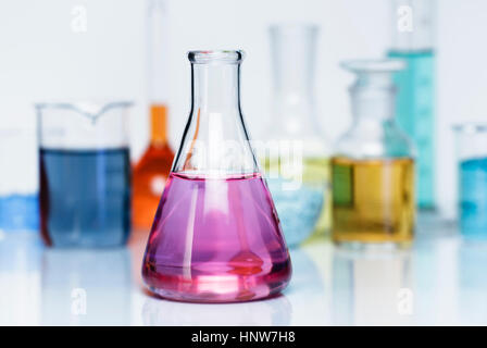 Erlenmeyer flask containing potassium permanganate solution, other flasks of transition metal salts, dry chemicals and solutions Stock Photo