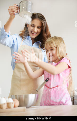 Mother and daughter baking together, sieving flour, fooling around Stock Photo