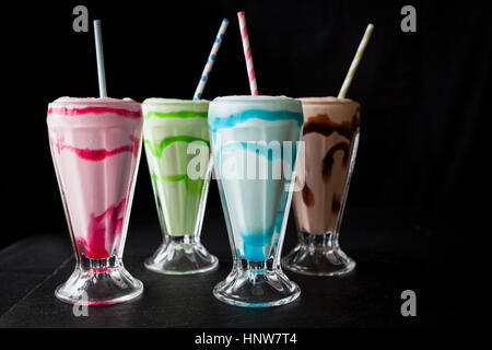 Four colourful milkshakes with drinking straws on table Stock Photo