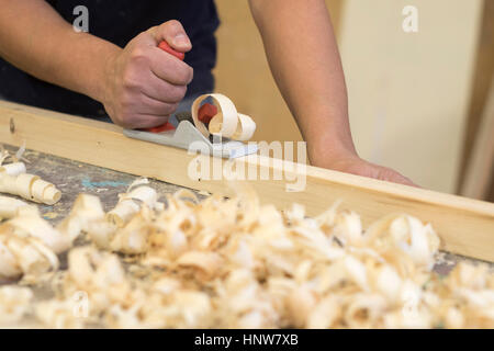 Hand of male carpenter using wood plane in workshop Stock Photo