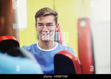 Over shoulder view of male boxer wearing punch mitt training with teammate Stock Photo