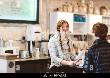 Cashier attending to customer in cafe Stock Photo