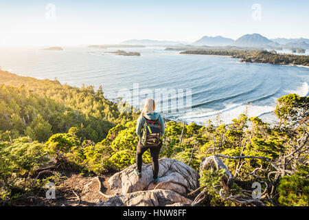 Female hiker looking out from coastal forest, Pacific Rim National Park, Vancouver Island, British Columbia, Canada Stock Photo