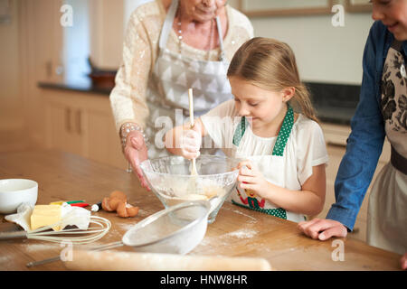 Senior woman and granddaughters stirring cookie mixture in bowl Stock Photo