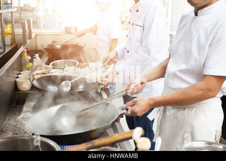 Group of chefs in hotel or restaurant kitchen busy cooking Stock Photo