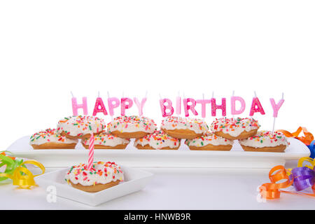 Miniature donut cake for first birthday party. with Happy Birthday multicolored candles, partially isolated on white background. Perfect size for kids Stock Photo