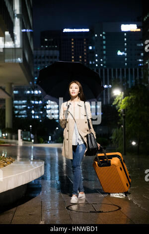Young woman with umbrella and carrier Stock Photo