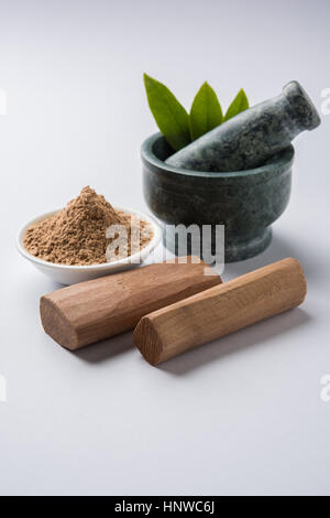 Chandan or sandalwood powder with traditional mortar, sandalwood sticks, perfume or oil and green leaves. selective focus