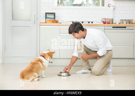 Smiling man feeding pet dog Stock Photo