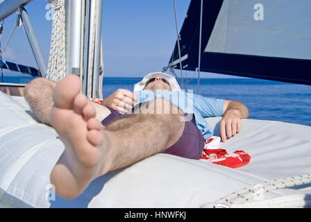 Model release, Mann beim Relaxen am Segelschiff - man relaxing on sailboat Stock Photo