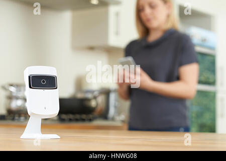 Woman Controlling Smart Security Camera Using App On Mobile Phone Stock Photo