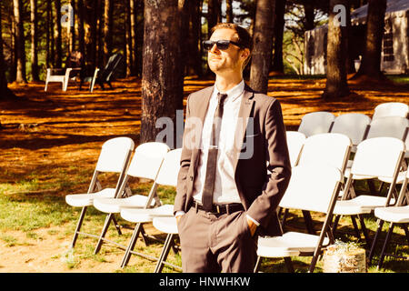 Mid adult man standing in front of rows of chairs, outdoors, in rural setting Stock Photo