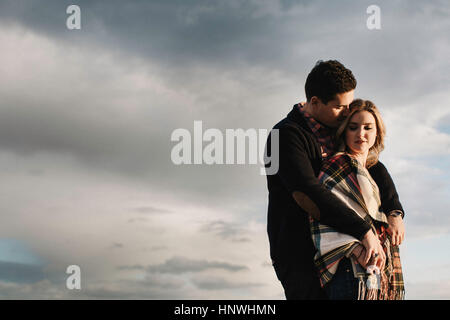 Young couple standing outdoors, embracing, holding hands Stock Photo