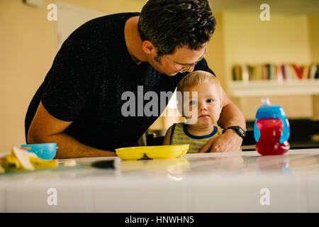 Father helping young son at meal time Stock Photo