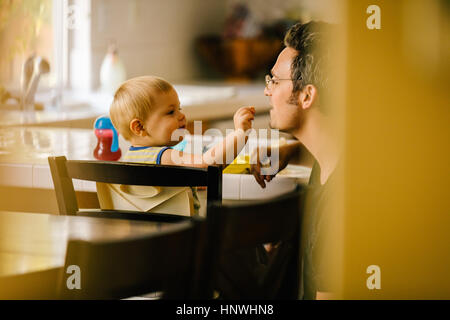 Father helping young son at meal time Stock Photo