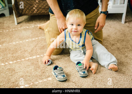 Father helping young son put on shoes Stock Photo