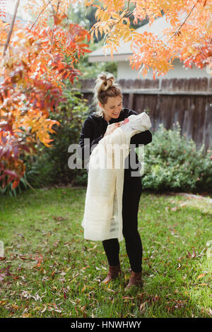 Mid adult woman carrying newborn baby daughter in garden Stock Photo