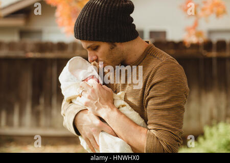 Mid adult man gazing at newborn baby daughter in garden Stock Photo