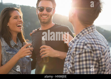 Three adult friends laughing and partying on roof terrace Stock Photo