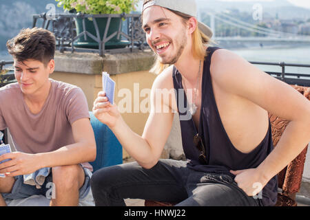 Two young men playing card game at roof terrace party, Budapest, Hungary Stock Photo