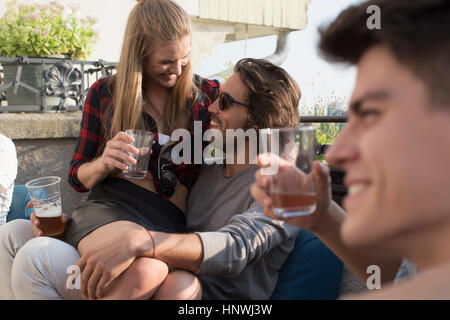 Adult friends relaxing with drinks at roof terrace party Stock Photo