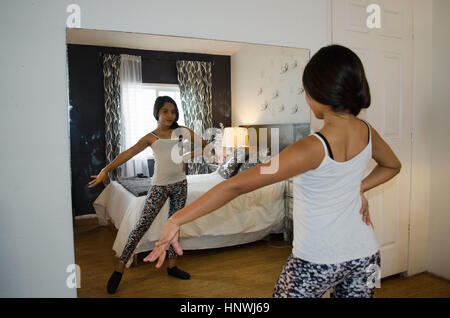 Young girl at home, practising dance moves in front of mirror Stock Photo