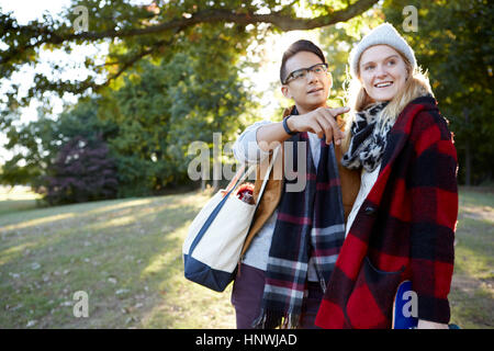 Young woman skateboarder and boyfriend pointing in park Stock Photo