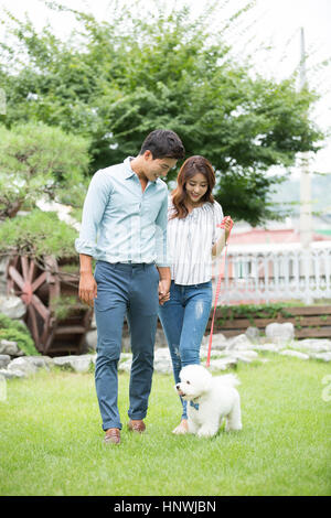 Young smiling couple walking pet dog Stock Photo