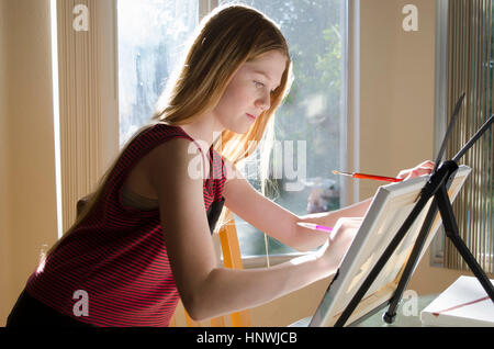 Teenage female artist drawing on canvas in conservatory