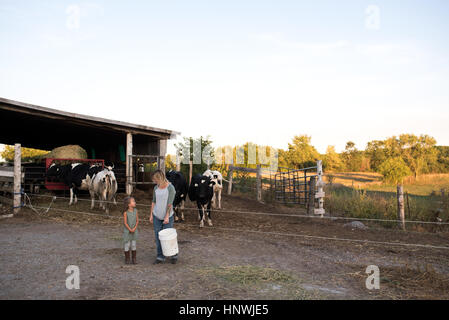 Mother and daughter standing together on farm, holding animal feed Stock Photo