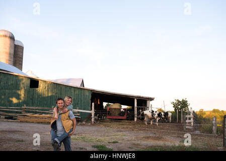 Couple on farm, man carrying woman on back Stock Photo