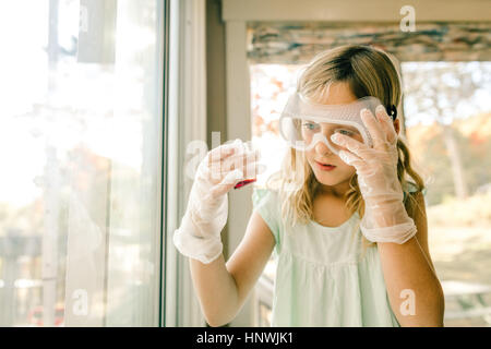 Girl doing science experiment, staring at measuring flask Stock Photo
