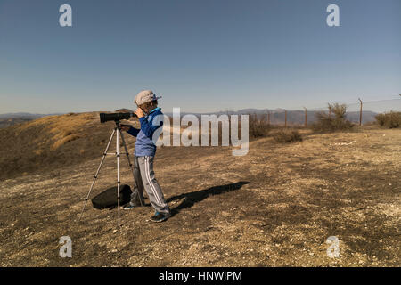 Boy looking through telescope on tripod Stock Photo