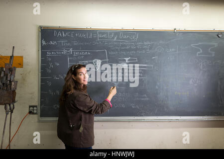 Female metal work teacher writing on classroom blackboard Stock Photo
