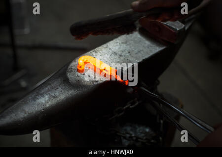 Red hot metal rod on metal workshop anvil Stock Photo