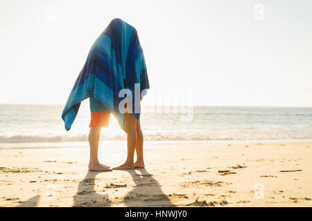 Couple hiding under blanket on Newport Beach, California, USA Stock Photo