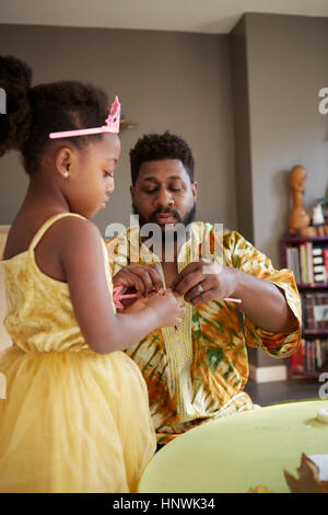 Mature man repairing fairy wand for daughter in kitchen Stock Photo