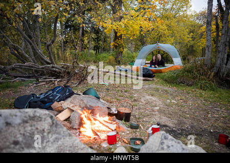 Campfire With Couple Relaxing In Tent At Forest Stock Photo