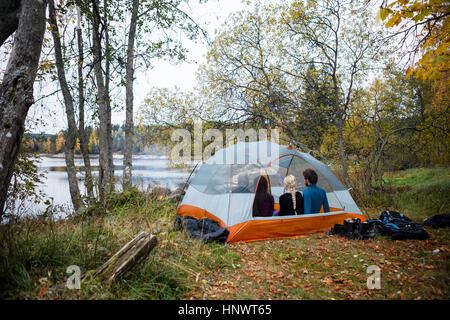 Friends Relaxing In Tent On Lakeshore Stock Photo