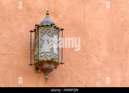 Lantern.  Brass and glass arabic style lantern on the exterior of a terracotta colored building wall Stock Photo