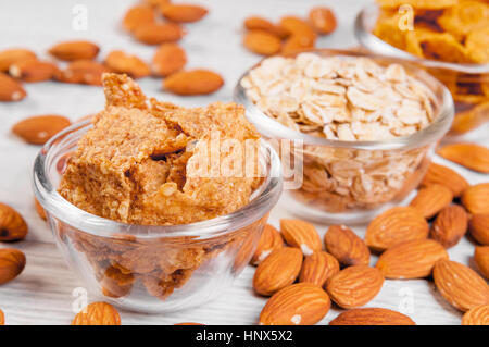 assortment breakfast cereals in small glass dishes on wooden table, almond nuts close up Stock Photo