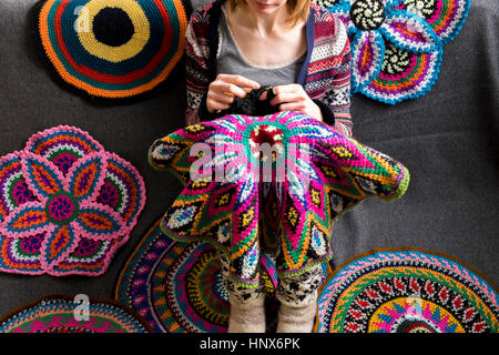 Cropped view of woman sitting on floor crocheting, surrounded by crochet circles Stock Photo