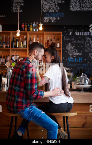 Couple on stools in coffee shop face to face smiling Stock Photo