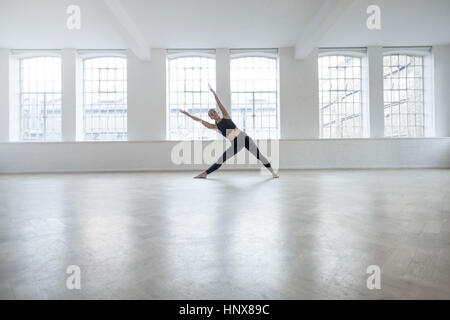 Woman in dance studio bending over sideways stretching Stock Photo