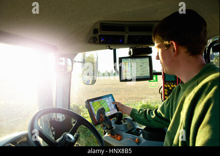 Young man driving tractor using touchscreen on global positioning system Stock Photo