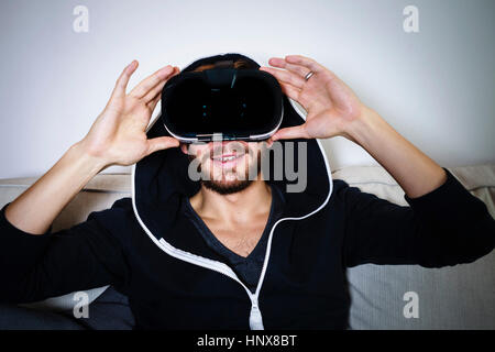 Mid adult man on sofa watching virtual reality headset Stock Photo