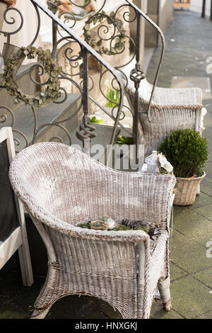 HATTINGEN, GERMANY - FEBRUARY 15, 2017: White painted woven willow chairs and green plants decorate a retail storefront Stock Photo