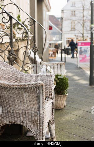 HATTINGEN, GERMANY - FEBRUARY 15, 2017: White painted woven willow chairs and green plants decorate a retail storefront Stock Photo